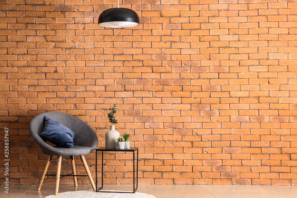 Armchair with table and floral decor near brick wall