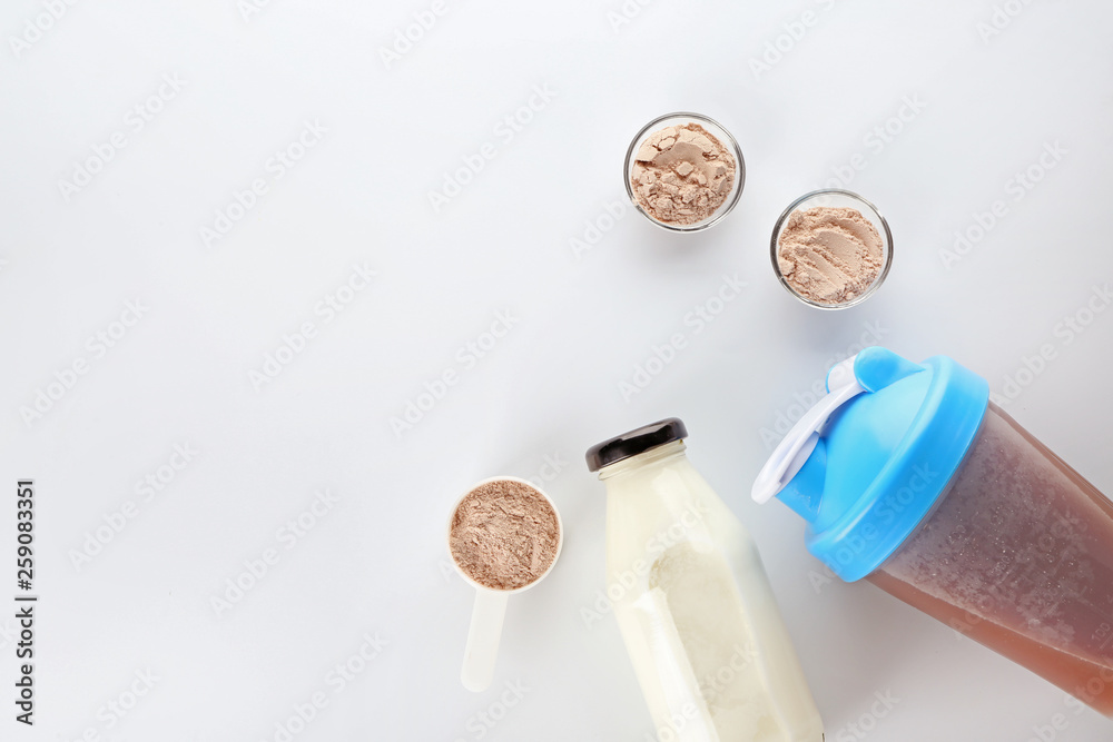 Bottles of protein shake and milk on white background