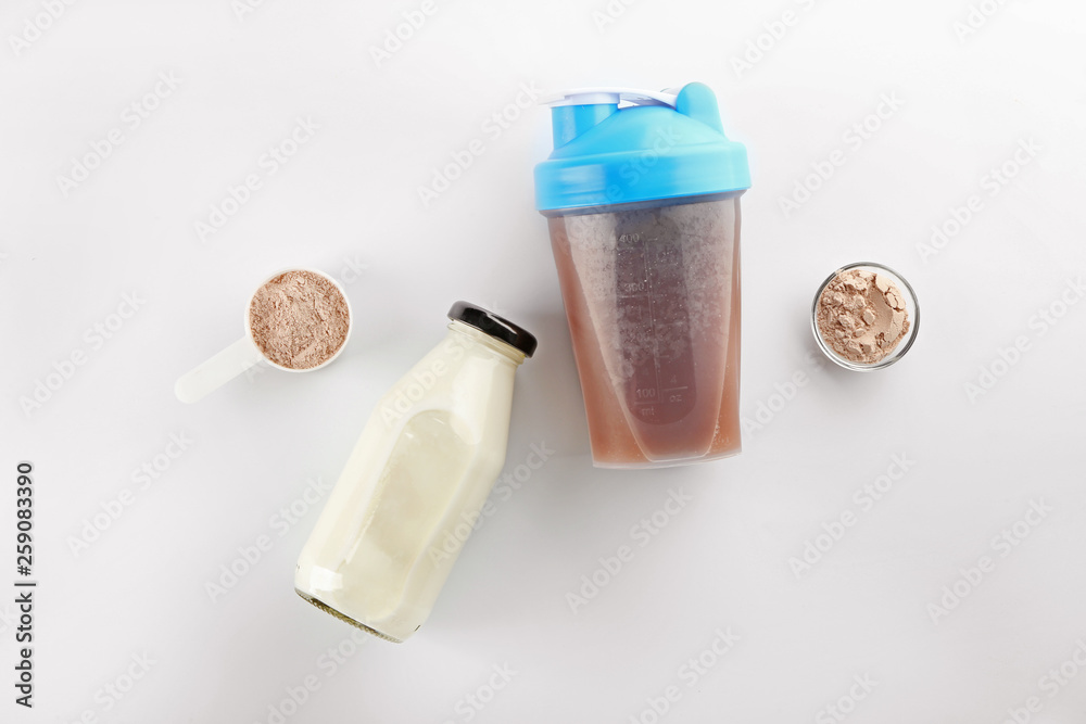 Bottles of protein shake and milk on white background