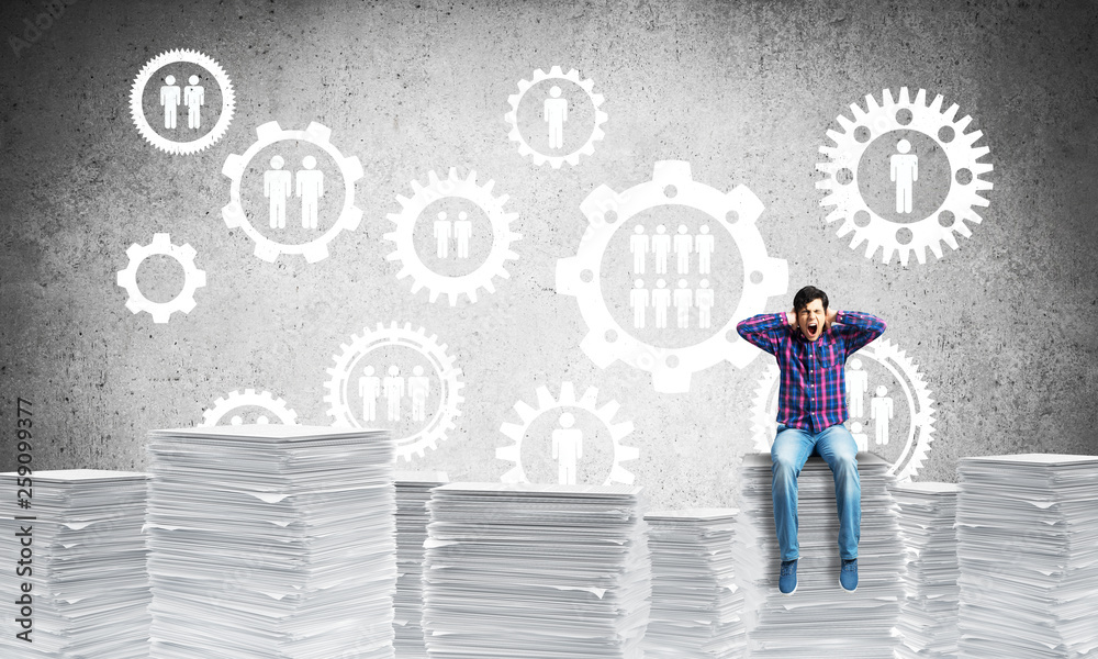 Attractive man sitting on pile of paper documents.