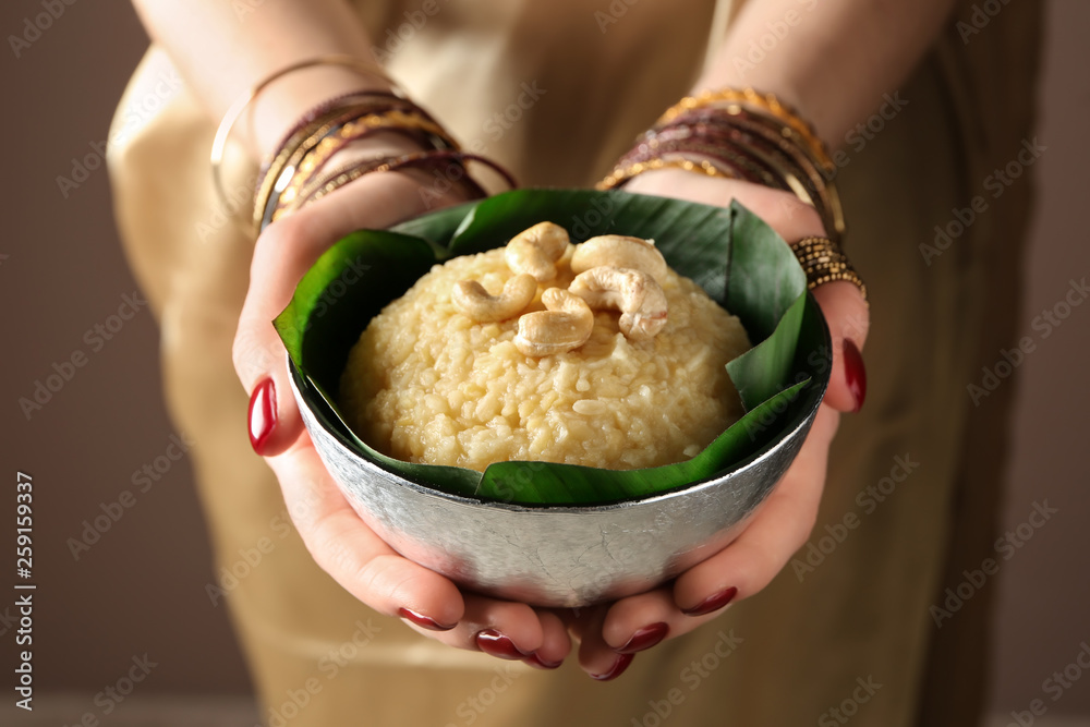 Woman holding bowl with traditional Indian food pongal, closeup