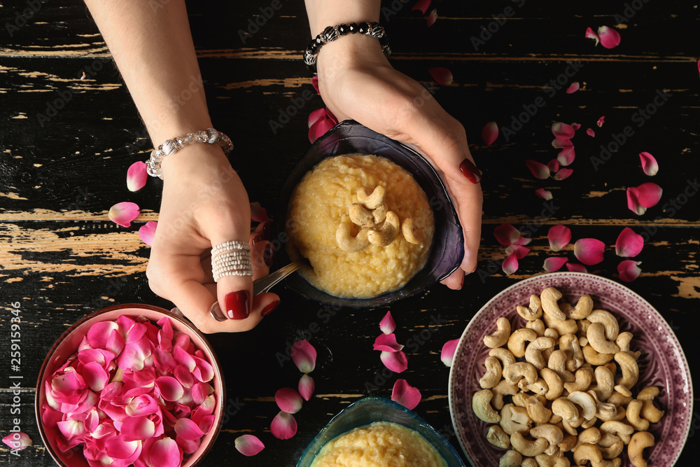 Woman with traditional Indian food pongal at table, top view