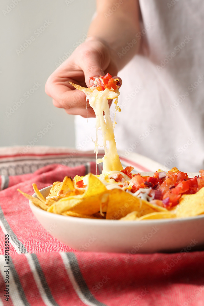 Woman eating tasty nachos with cheese, closeup