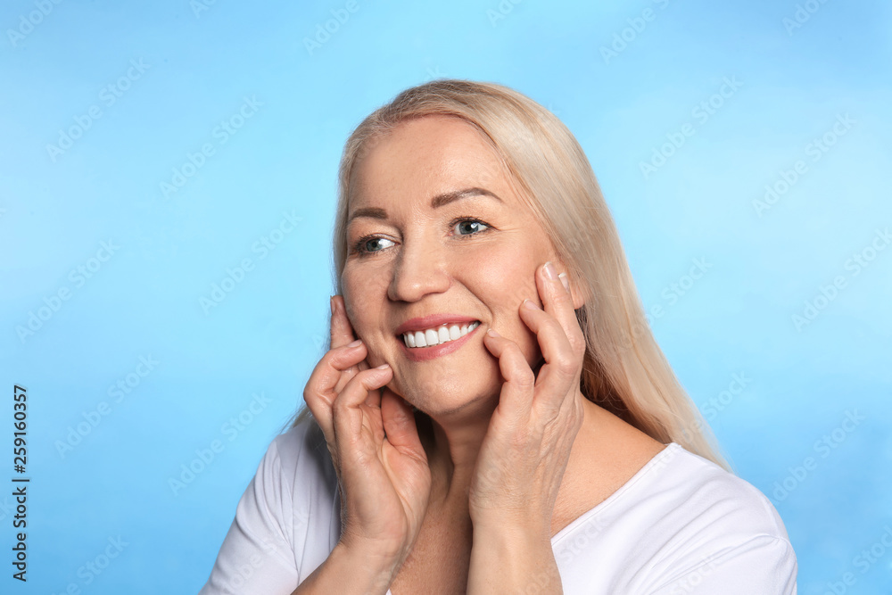 Mature woman with healthy skin on color background