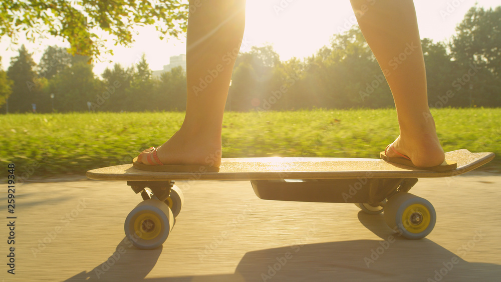 CLOSE UP: Unrecognizable active woman skating through the tranquil sunlit park.