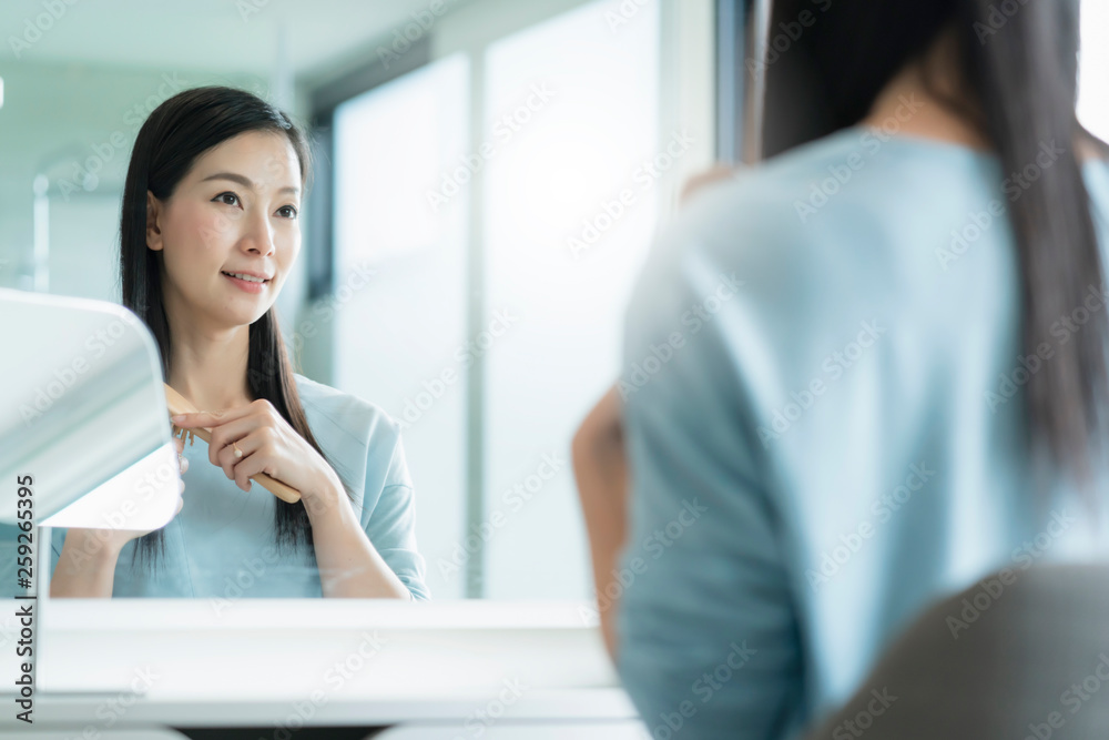 美丽的亚洲女性化妆和发型，浴室里有镜子，有晨光