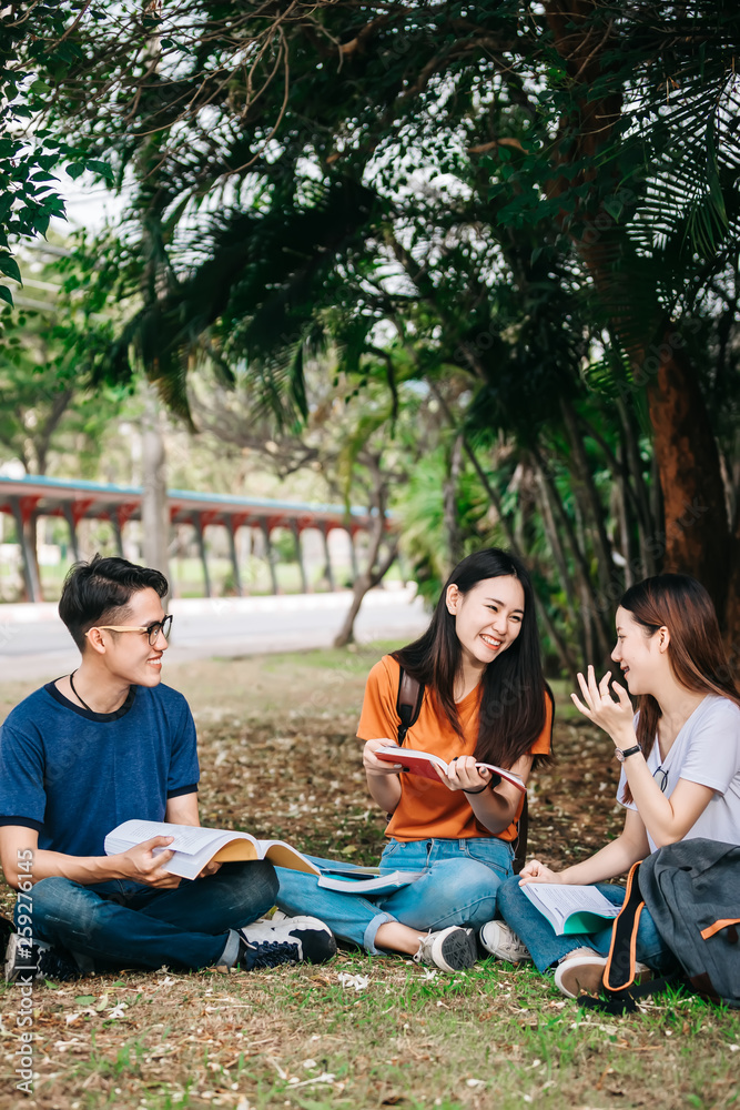 一群年轻或十几岁的亚洲学生在大学里微笑着读着书，看着ta