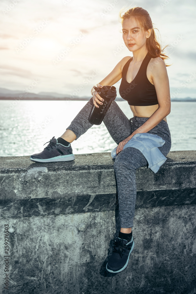 Asian woman is workout and running at the morning, she is warm up her body and drinking water. Healt