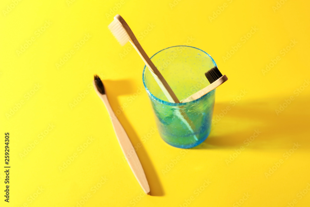 Holder with toothbrushes on color background