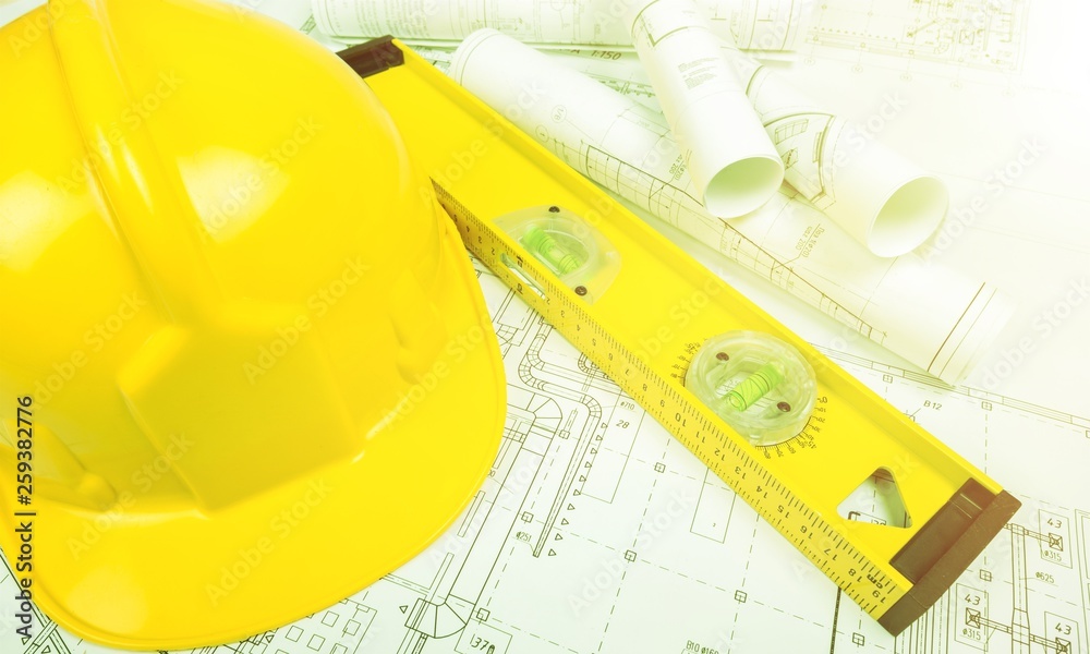 Yellow hard hat and blueprints in a construction concept