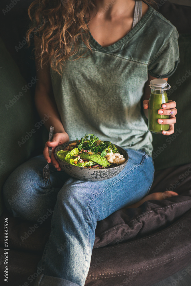 健康的晚餐或午餐。穿着t恤和牛仔裤的女人坐着，手里拿着素食超级猫头鹰或佛波