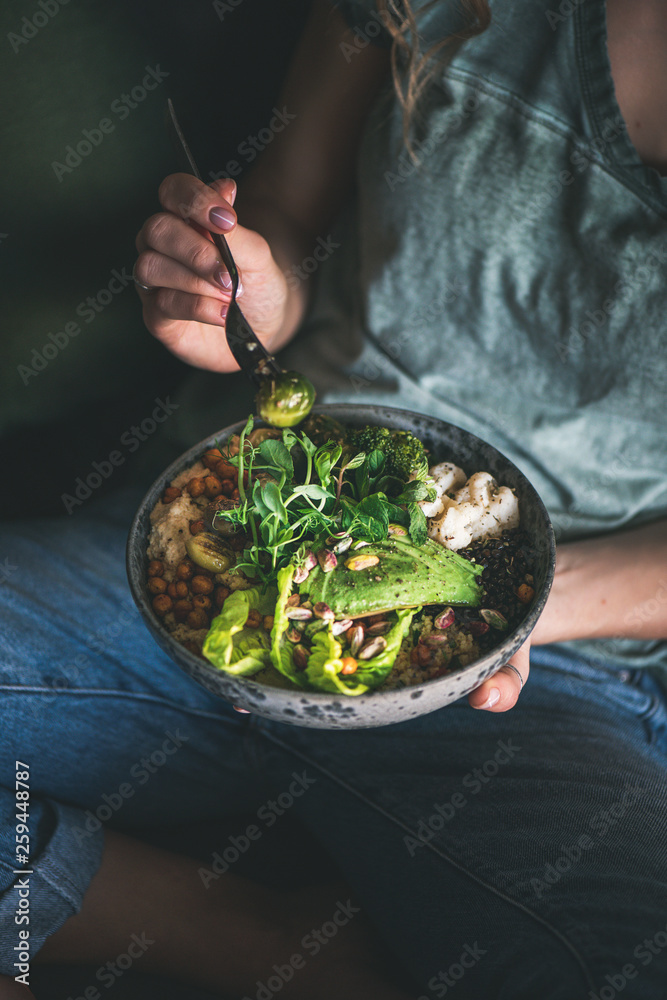 健康的晚餐或午餐。穿着t恤和牛仔裤的女人坐着吃素食超级猫头鹰或佛弓