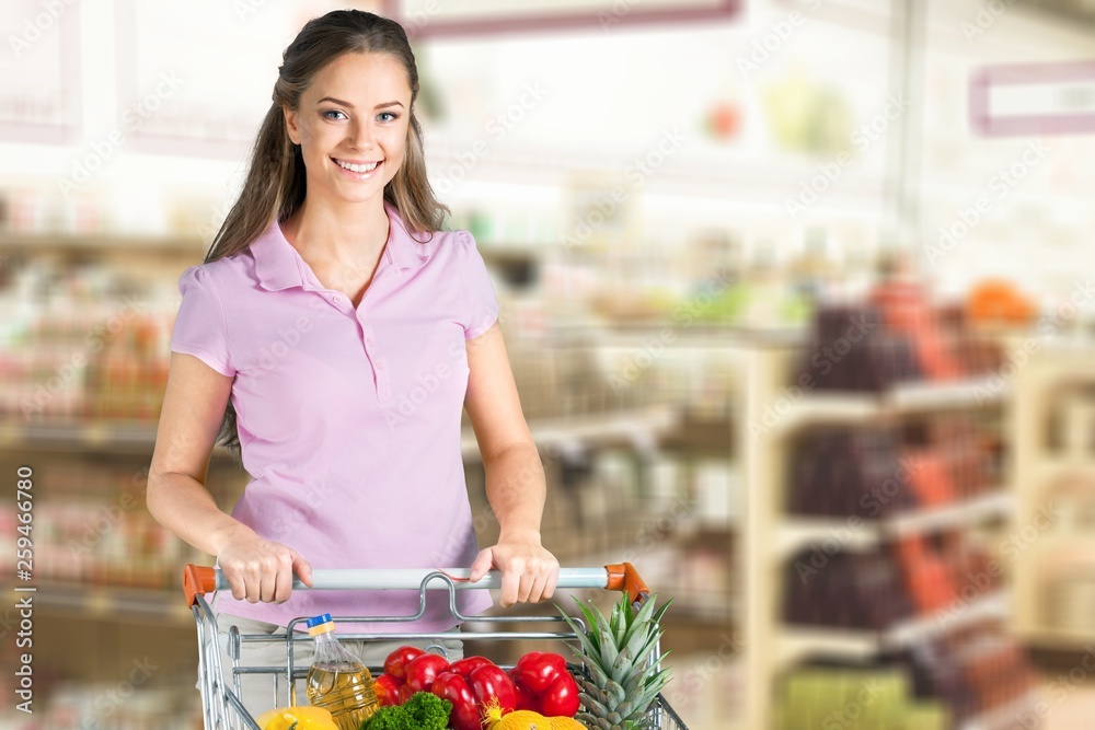 Young happy woman with shopping cart, holding jar