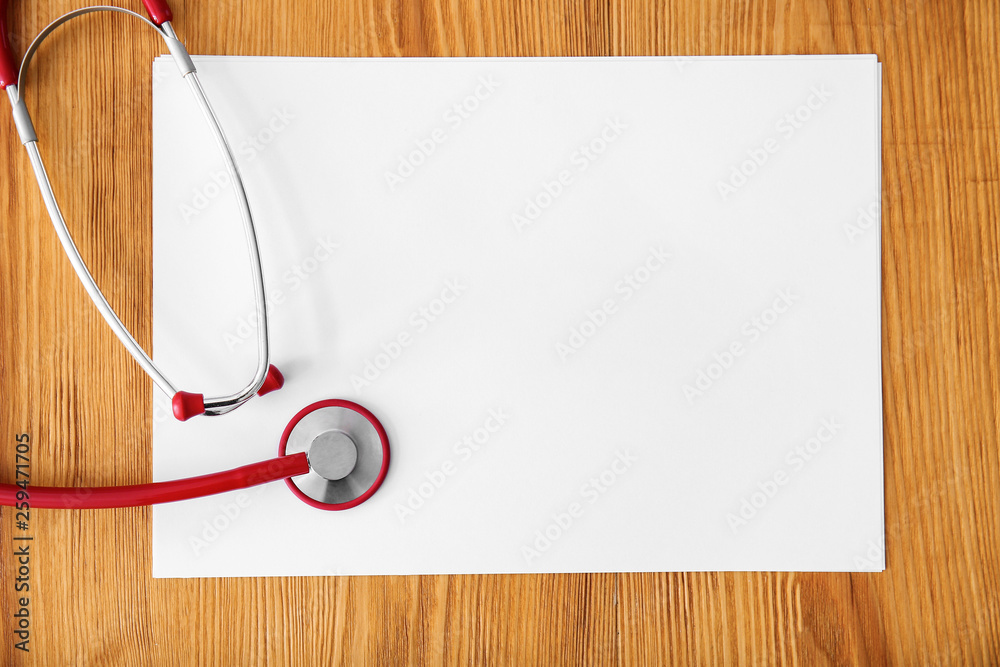 Stethoscope with sheet of paper on wooden background