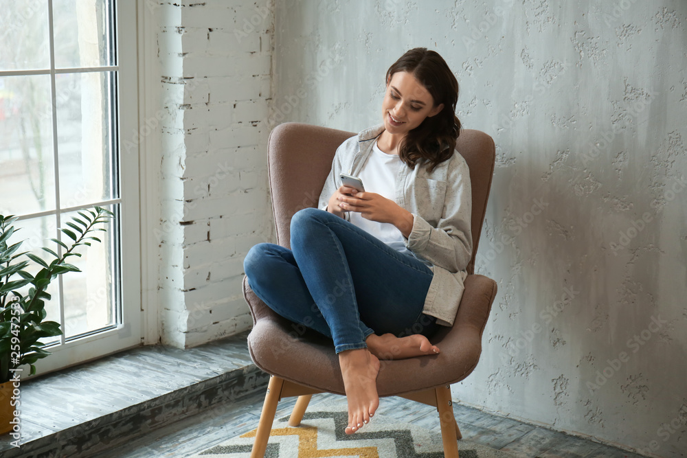 Beautiful young woman with mobile phone resting at home