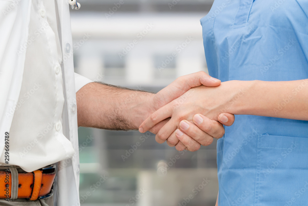 Doctor in hospital handshake with another doctor. Healthcare people teamwork and medical service con