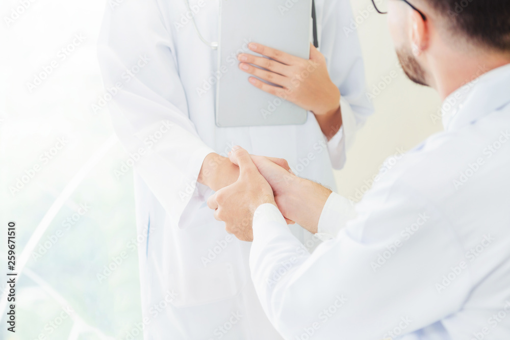 Doctor at the hospital giving handshake to another doctor showing success and teamwork of profession