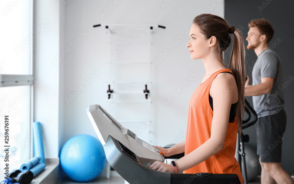 Sporty young woman training on treadmill in gym