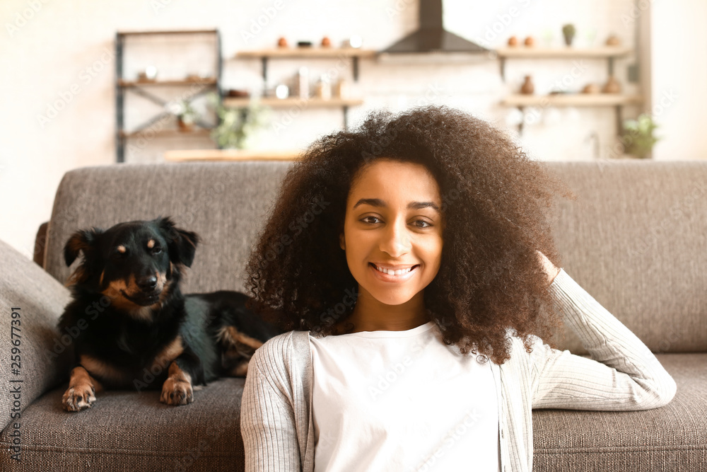 Beautiful African-American woman with cute dog at home