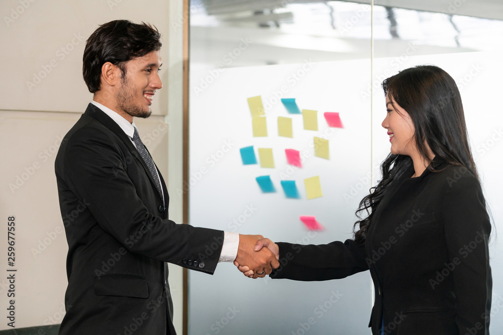 Business people agreement concept. Businessman and Asian businesswoman do handshake in the office.