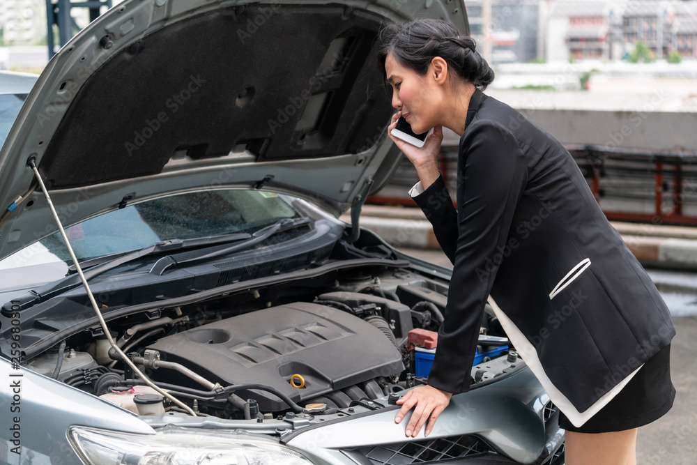 Young businesswoman whose car breakdown uses mobile phone to call for roadside assistance service. T