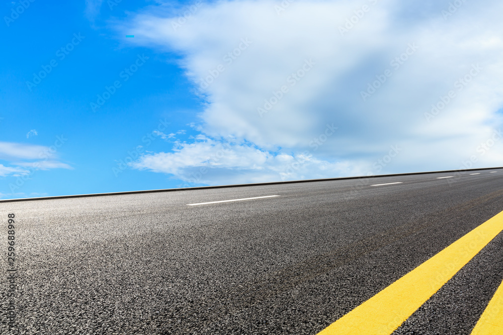 Empty asphalt road and blue sky with white clouds scene