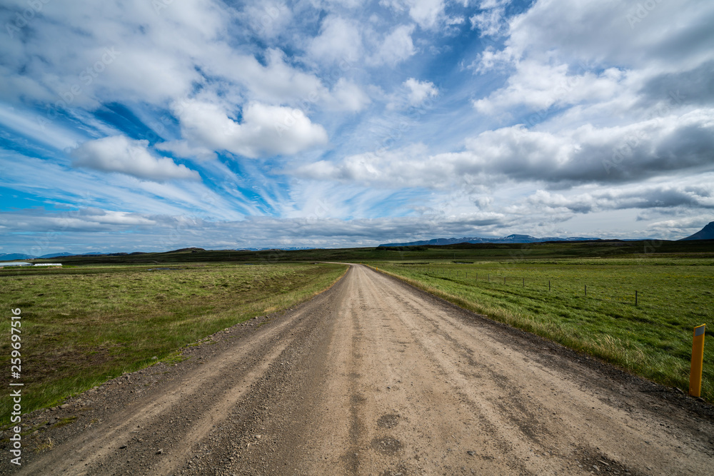 Empty gravel dirt road through countryside landscape and grass field. Nature off road travel trip fo