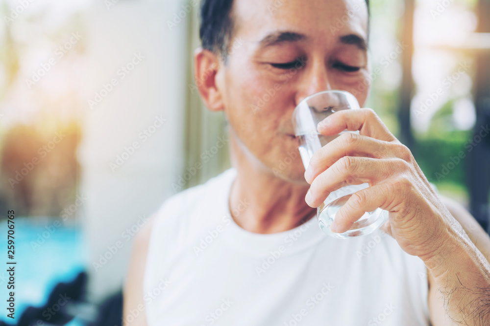 老年人运动后在健身房健身中心喝矿泉水。老年人健康的生活方式。