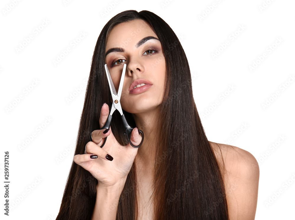 Portrait of beautiful young woman with healthy long hair and scissors on white background