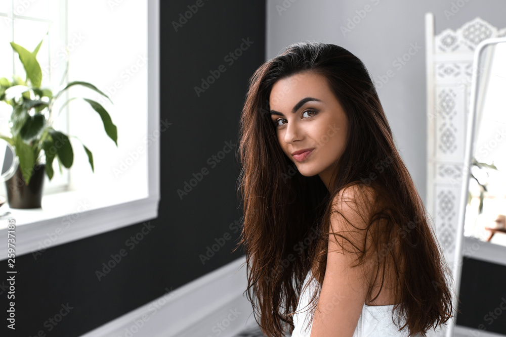 Beautiful young woman with healthy long in bathroom