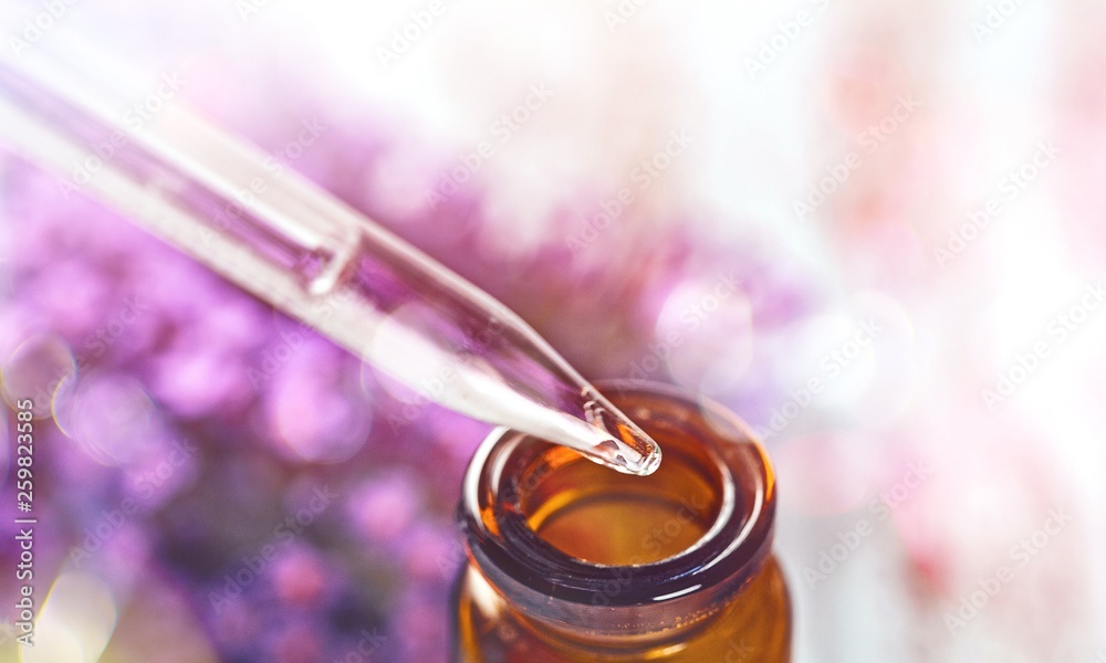 Pile of lavender flowers and a dropper bottle with lavender essence