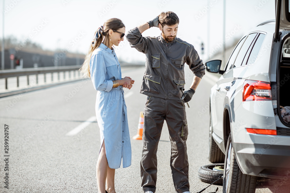 身穿制服的道路救援人员与年轻女子站在高速公路上破碎的汽车附近