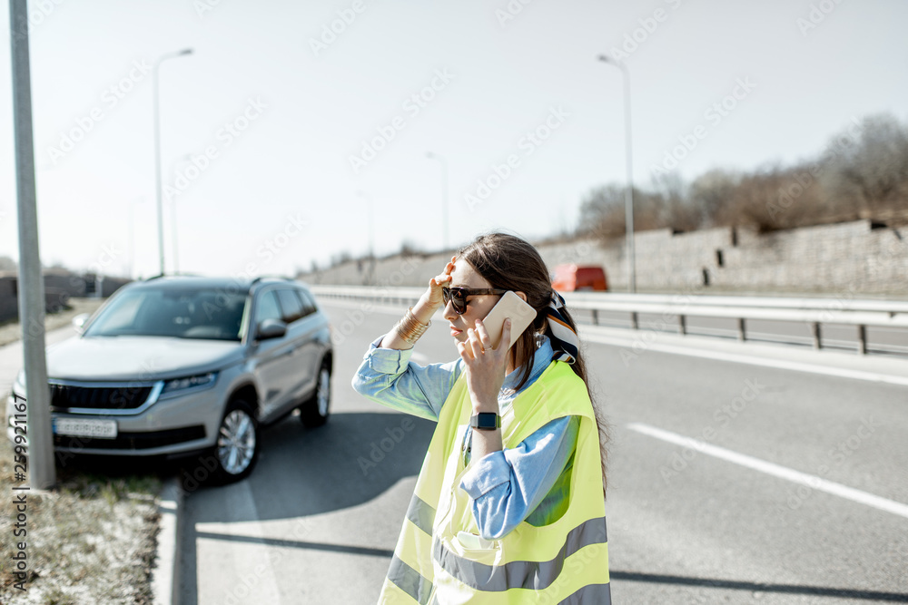 在高处发生道路事故时，一名尴尬的女子站在汽车附近呼叫道路救援