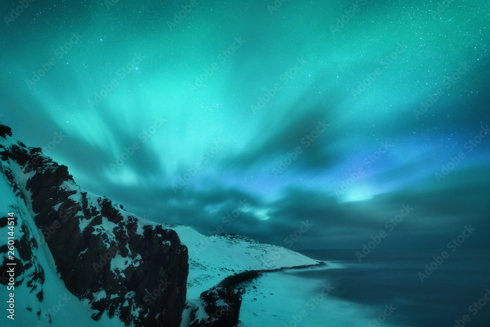 Amazing aurora borealis. Northern lights in Teriberka, Russia. Starry sky with polar lights and clou