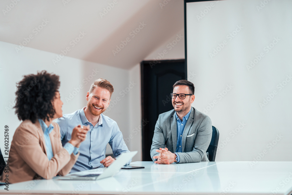 Smiling colleagues having conversation in bright office.