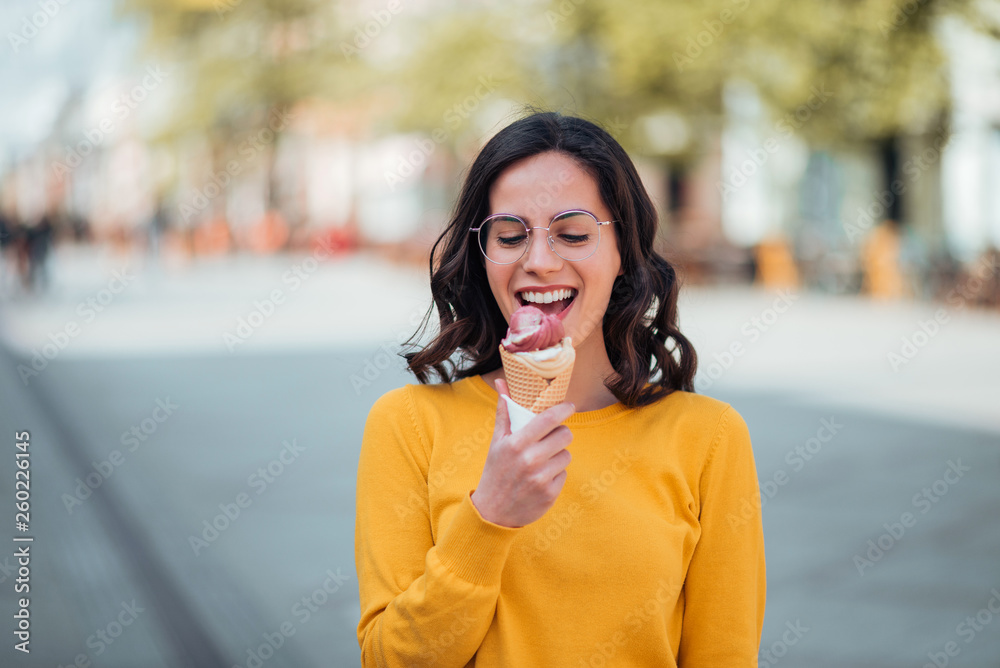 千禧一代的女人在春天阳光明媚的日子里吃冰淇淋。