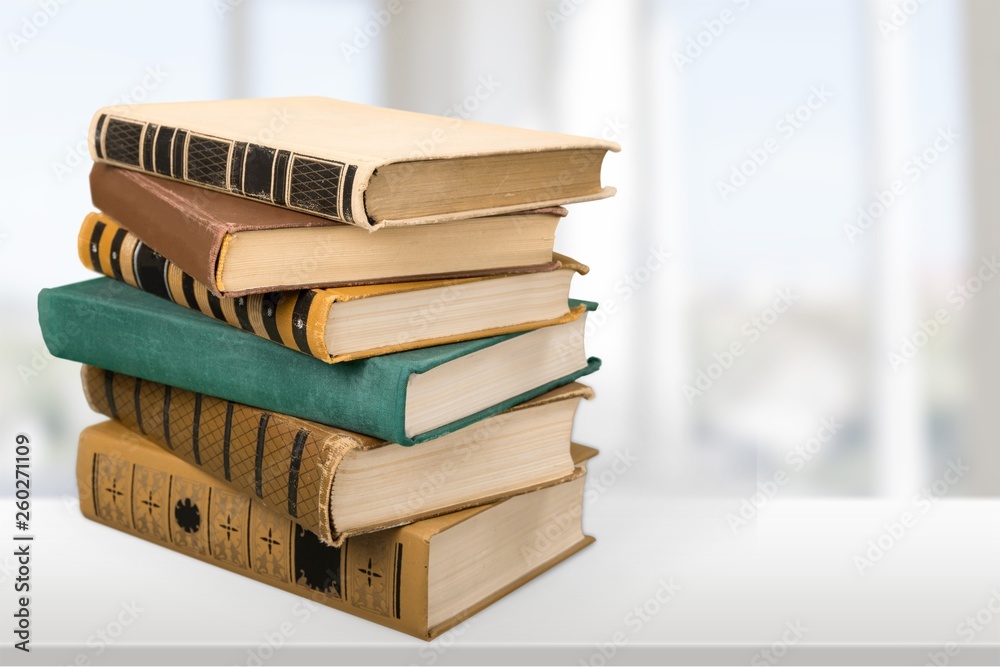 Stack of books with laptop on table