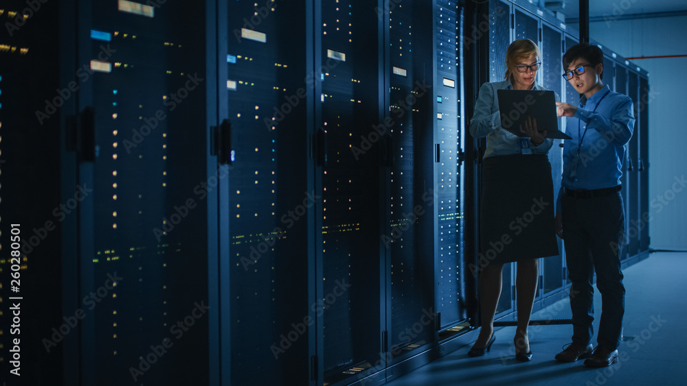 In the Modern Data Center: Engineer and IT Specialist Work with Server Racks, Talking, Doing System 