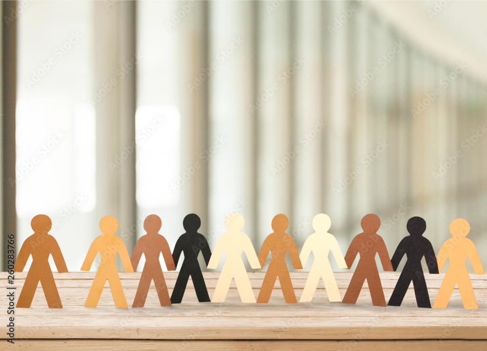 Row of paper people holding hands on table on light background