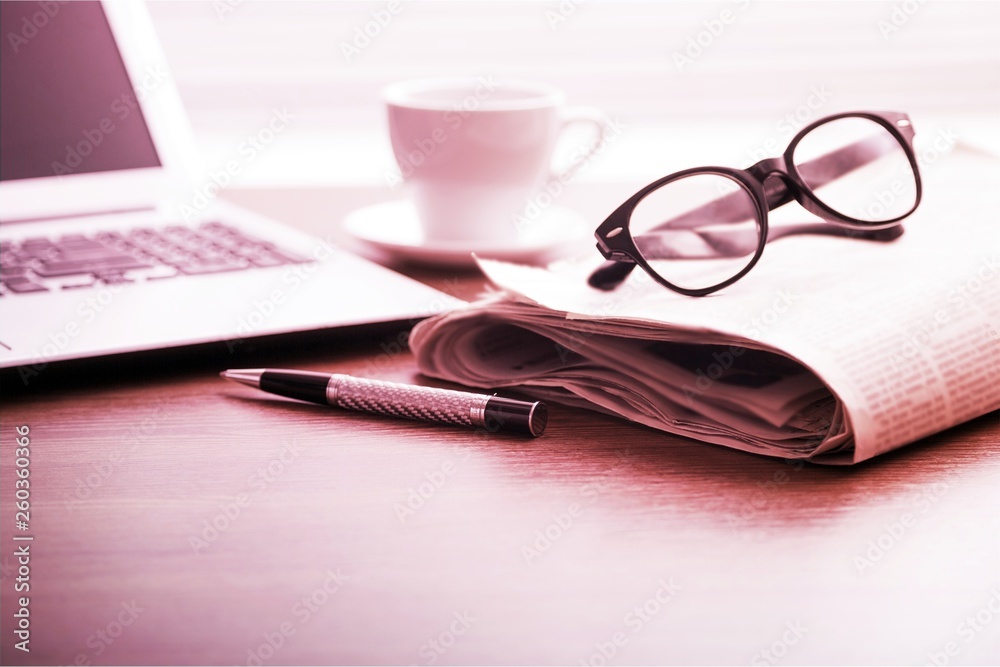 Newspapers with glasses and laptop