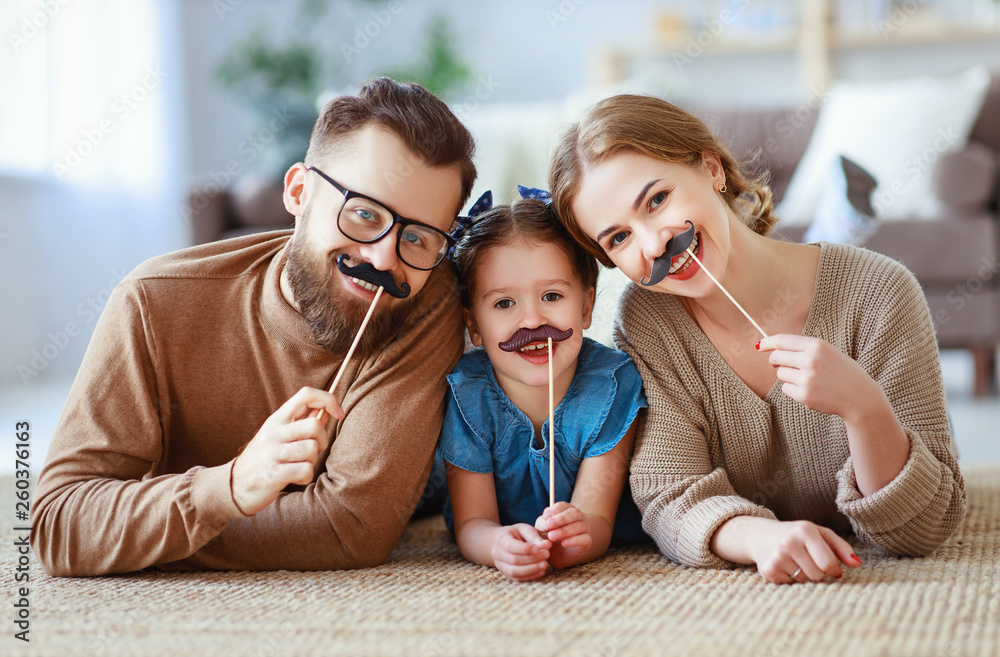 happy funny family mother father and child daughter with mustache on stick