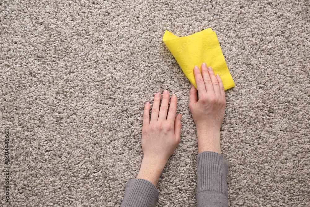 Female hands with rag on carpet