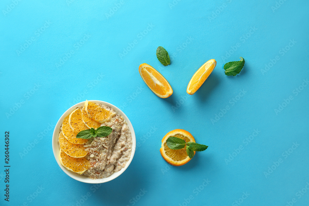 Bowl with tasty sweet oatmeal and orange fruit on color background