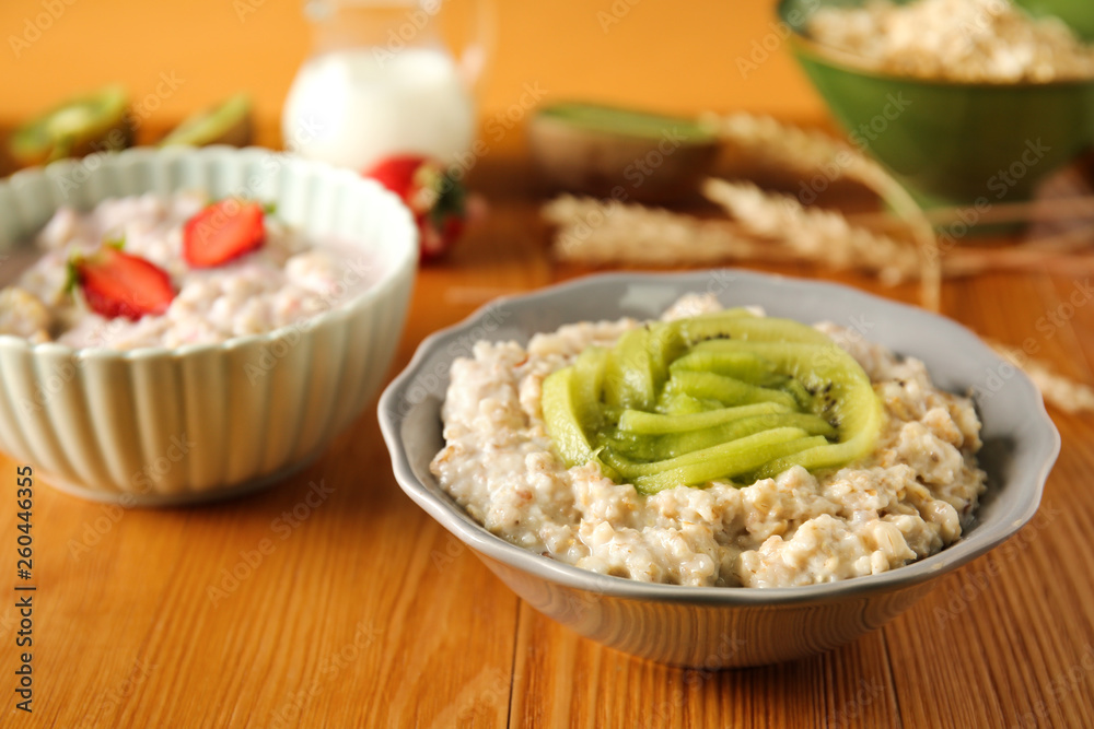 Bowl with tasty sweet oatmeal on wooden table