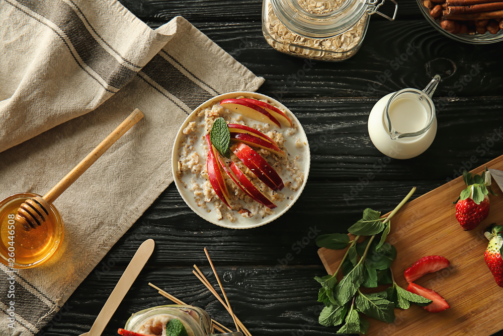 Tasty sweet oatmeal with ingredients on wooden table