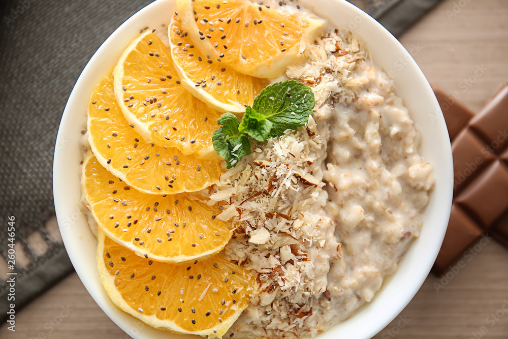 Bowl with tasty sweet oatmeal on table, closeup