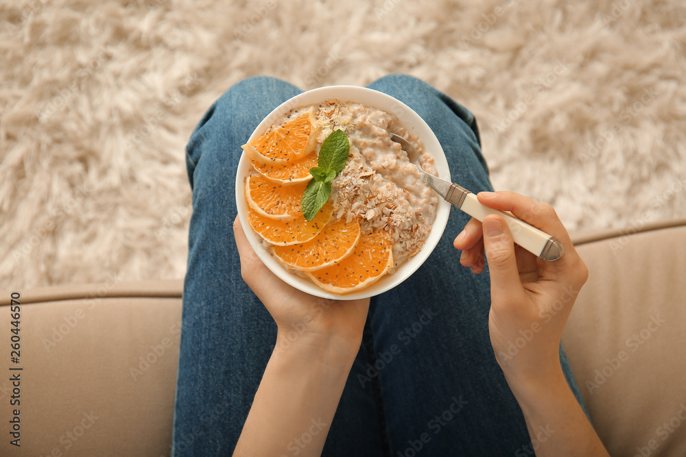 Young woman eating tasty sweet oatmeal at home