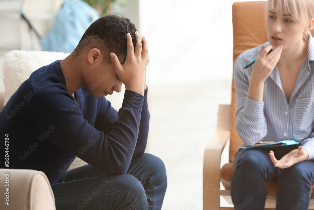 Female psychologist working with depressed teenage boy in office