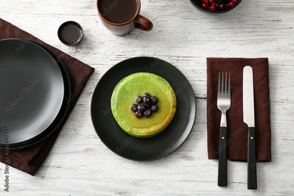 Tasty green pancakes on white table