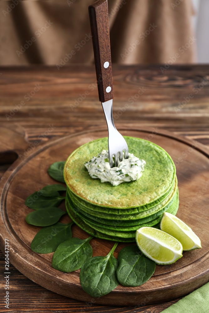 Tasty green pancakes on wooden board